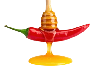 A vibrant red chili pepper drizzled with golden honey, showcasing a striking contrast of colors and textures. © TransPicHub