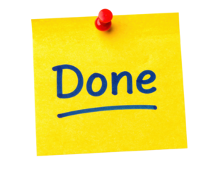 A bright yellow sticky note with the word "Done" written in bold, blue letters, secured with a red pushpin.