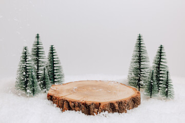 Empty wooden winter podium in the snow with christmas trees at the background. Christmas and new year background for product presentation, gift and design