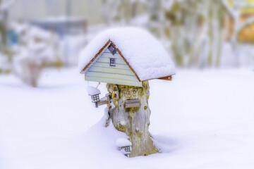 A small wooden house for Christmas gnomes covered in snow in a winter garden