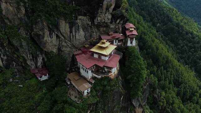 Aerial view of the Tigers Nest monastery perched dramatically on a cliffside, blending seamlessly with the forest, Paro, Bhutan.