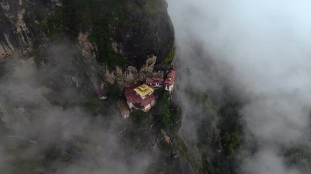 Aerial view of Tigers Nest temple perched dramatically on a cliffside, shrouded in ethereal mist, a symphony of nature and architecture, Paro, Bhutan.
