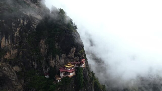 Aerial view of Tigers Nest monastery clinging to a steep cliff face, shrouded in ethereal mist, a testament to architectural wonder, Paro, Bhutan.