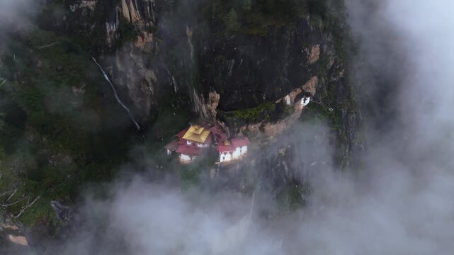 Aerial view of the iconic Tigers Nest monastery clinging to the cliffside, shrouded in mist, a testament to architectural marvel, Paro, Bhutan.