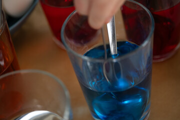 Close-up of blue dye with spoon during Easter egg coloring at home