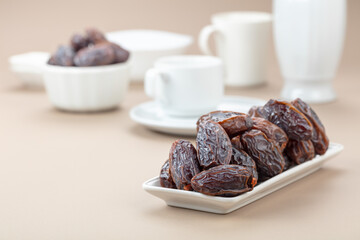Dates in white dish on a beige background.