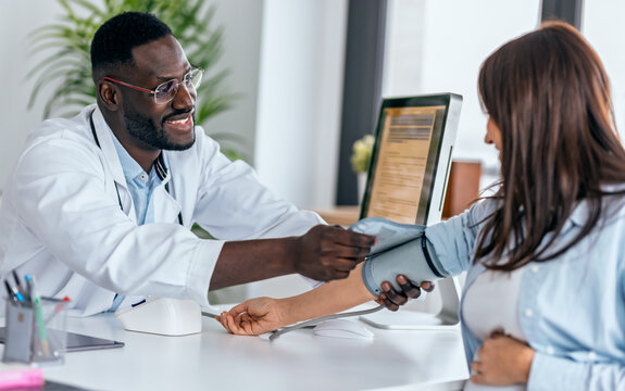 Shot of gynecologist checking the blood pressure of her pregnant patient in the clinic.