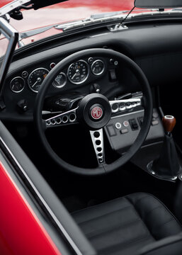 Steering wheel and dashboard of red MG roadster. 1960s classic sports car's black leather interior. Kyiv, Ukraine - September 30 2024