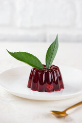 Delicious jelly with cherry and green leaves in a light table. Healthy food, sugar, gelatin and lactose free. Vertical orientation.