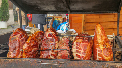Juicy ham cooked on an open grill at a traditional street market. The crispy, golden-brown crust and smoky aroma create a delicious street food atmosphere.