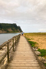 Obraz premium Rodiles Beach in Villaviciosa, Spain, under cloudy weather with soft waves, wet sand, and a calm, moody coastal atmosphere.