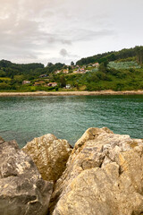Obraz premium Rodiles Beach in Villaviciosa, Spain, under cloudy weather with soft waves, wet sand, and a calm, moody coastal atmosphere.