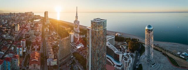 Aerial view of Batumi, Georgia with modern skyscrapers and coastline at sunset.