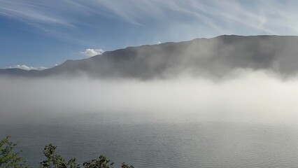 Dramatic deep blue fjord with steep towering green mountains and still water reflections.