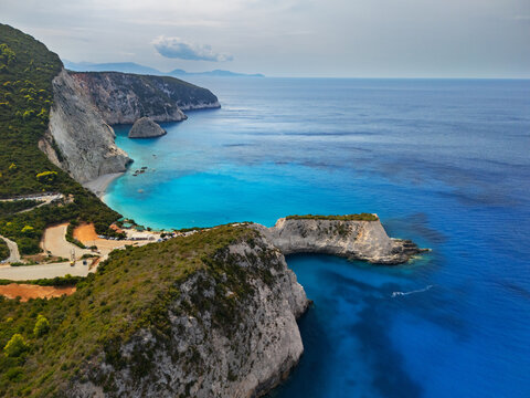 Aerial view of turquoise waters meeting the dramatic cliffs of Porto Katsiki beach under a soft sky, Lefkada, Lefkada, Greece.