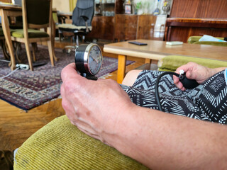 Senior Person Measuring Blood Pressure At Home With Manual Sphygmomanometer In Living Room
