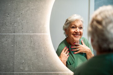 Happy senior woman looking in mirror