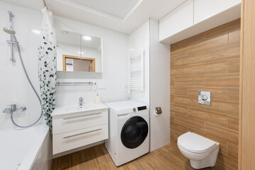 Modern Home Bathroom Washroom Decor Featuring a Washer, Sink, Toilet, and Wood Paneling