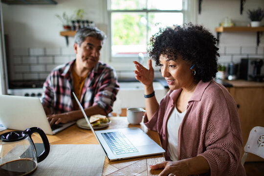 Middle aged couple working on laptops at home - Powered by Adobe