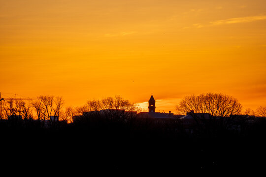 View of the silhouetted skyline, a mix of bare trees and buildings, with a prominent tower, all bathed in the fiery glow of the sunset, Washington, D.C., United States.