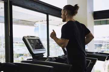 Young man running on treadmill in the gym