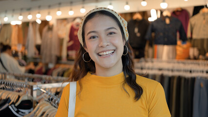 Young teen Gen Z asia female happy smile looking at camera at zero waste eco go green buy second hand sale store flea market mall thrift old used vintage fabric retro style. Woman people enjoy shop.