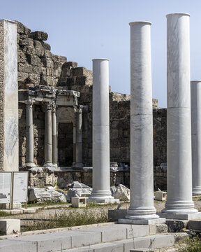 View of striking white marble columns stand proudly against the weathered ruins under a clear sky, whispering tales of ancient glory, Side, Antalya, Turkey.