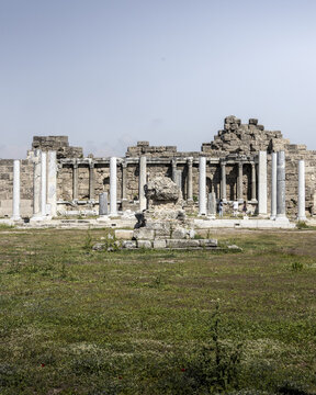 View of ancient ruins standing tall, a testament to time, against the vast sky in a ground-level perspective, Side, Antalya, Turkey.