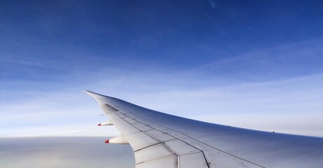 Obraz premium plane wings in the aerial view with clouds in the sky at sunset, with copy space taken from plane window 