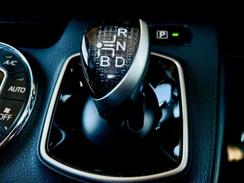 A close-up of a modern vehicle's center console featuring the circular automatic climate control panel with 'AUTO' and 'DUAL' zones, positioned next to a sleek electronic gear selector 