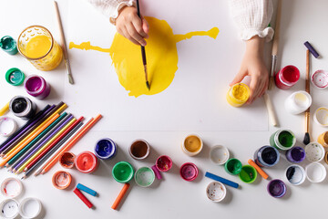 Child drawing with various art materials for creative and sensory development. Toddler activity with colorful gouache.