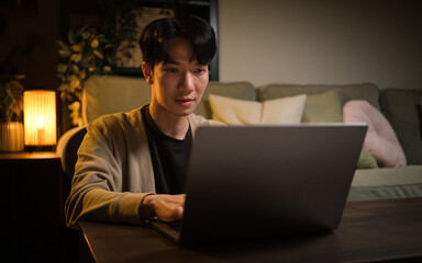Focused young man working on his laptop in a cozy living room at night.
