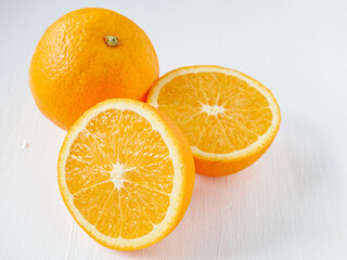 Halved orange fruit on white wooden background, close-up