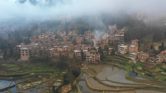 Drone shot of classic stone houses with straw rooftops in small village, set in rice terraces of Yuanyang in Southern China