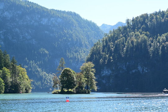 Kleines Modelsegelschiff mit orangen Segeln auf einen Bergsee