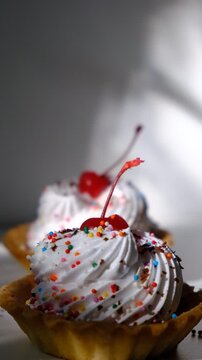 Cupcakes, sand baskets with cream with Cherry Topping. Dusk. Sunset sunlight and atmospheric mood. Cupcakes  with white pink meringues on top and chocolate, muffins