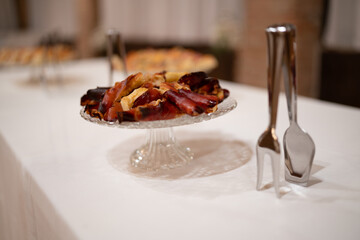 Deliciously Baked Fruit Tart on a Glass Pedestal Stand with Serving Utensils Ready for a Celebration Buffet or Event Dessert Table Spread