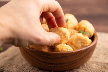 Fried crispy Chicken Nuggets with ketchup, microgreen on brown wooden with hand. Diet, healthy eating. side view, selective focus