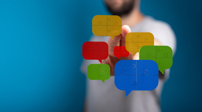 Conceptual image showing a hand interacting with colorful speech bubbles made of puzzle pieces, symbolizing communication and connection.