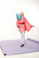 Charming pose with a japanese fan for the camera in studio