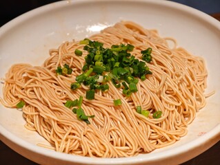 Chinese noodles topped with chopped scallions in bowl