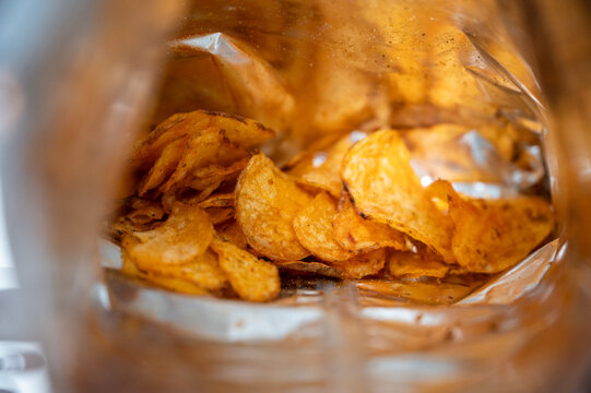 Open bag of potato chips showing crispy golden slices &mdash; tempting salty snack symbolizing both tasty indulgence and unhealthy junk food habits