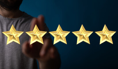 Hand reaching towards five gold stars to represent quality rating, positive feedback or high level...