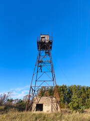Lonely watchtower rising above the grassy landscape on a bright sunny day, evoking a sense of solitude, forgotten history, and open freedom under vast blue skies.