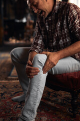 Man at home holding painful injured knee.