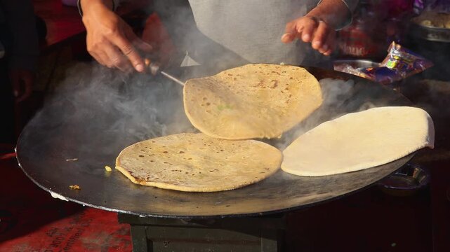 A village man prepares paratha on a hot pan at a food stall during a vibrant Indian mela. The scene reflects traditional cooking, local culture, and festive village life.