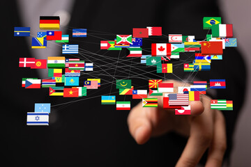A digital illustration showing a hand connecting a global network of international flags,...