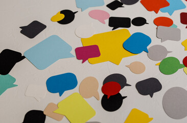 Abstract image of various colored speech bubbles on a textured white background. Suitable for design, communication, discussion, or concept. Ide