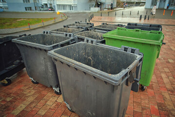 Plastic garbage containers with open lids stand on residential street after trash collection,...