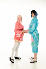 Youthful kindred spirits in colorful kimonos holding hands intimately